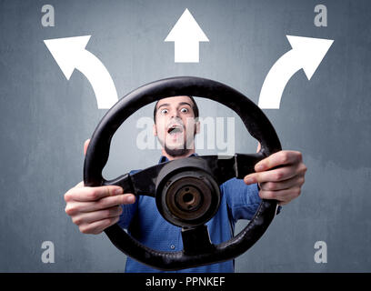 Junger Mann, schwarzes Lenkrad mit drei Pfeilen über seinem Kopf weisen in verschiedene Richtungen. Stockfoto