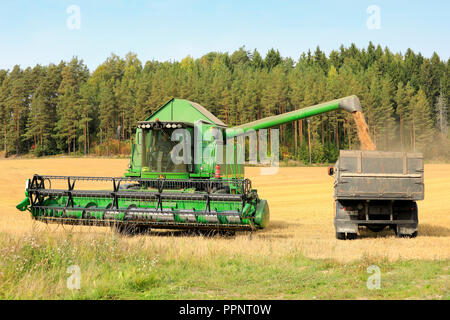 Salo, Finnland - 8 September, 2018: John Deere Mähdrescher entlädt geernteten Getreide auf LKW-Anhänger an einem klaren Tag der Herbst im Süden Finnlands. Stockfoto