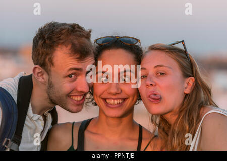 Zwei junge Frauen und ein junger Mann in die Kamera schauen, machen eine Grimasse, Freunde, Plaza de la Encarnacion, Sevilla, Andalusien Stockfoto