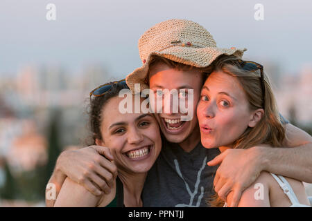 Zwei junge Frauen und ein junger Mann glücklich in die Kamera, Freunde suchen, Plaza de la Encarnacion, Sevilla, Andalusien, Spanien Stockfoto