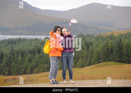 Japanische Touristen unter SELFIE Fotografien in den schottischen Highlands RE TOURISMUS REISEBUS REISEN URLAUB Aussichtspunkt einen herrlichen Blick GROSSBRITANNIEN Stockfoto