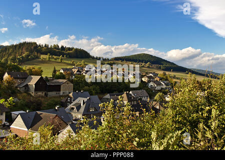 Schwalefeld, Deutschland - kleines Dorf in den grünen Hügeln der Region Sauerland mit bewaldeten Hügeln und blauen Himmel im Hintergrund eingebettet Stockfoto