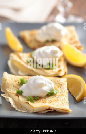 Crepes mit Creme fraiche, grüne Zwiebeln und Zitronen Stockfoto