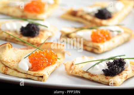 Crepes mit roter und schwarzer Kaviar auf einer Platte Stockfoto