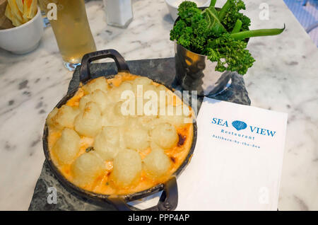 Fisch Torte überbacken mit Parmesan Mash und serviert mit grünen und eine Hälfte ein Pint Lager seaside Mahlzeit im Seaview Café Saltburn North Yorkshire UK Stockfoto