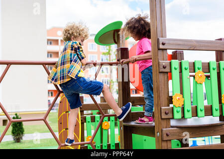 Curly multiethnischen kleine Kinder klettern und Spaß an der Spielplatz Stockfoto