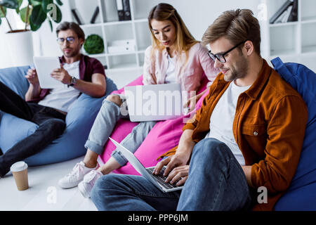 Multikulturelle Kollegen arbeiten an Startprojekt in Büro- und sitzen auf Sitzsäcken Stockfoto