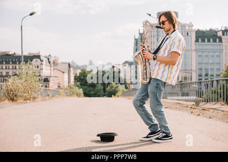 Junge glücklich männlichen Gaukler Saxophon spielen an Ort Straße Stockfoto