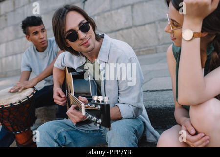 Team von jungen multirassischen Freunde ausruhen und spielen Musik in städtische Umwelt Stockfoto