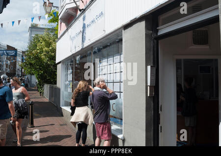 Frau und Mann betrachten racing Zeitpläne in Royal Ocean Racing Club Fenster, High Street, Cowes, Woche 2013 Cowes, Isle of Wight, Großbritannien angezeigt Stockfoto