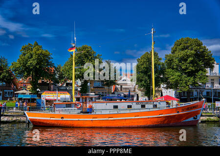 Bunte Boot im ruhigen Kanal ruht auf diesen Frühling heißen Tag in Warnemünde, Rostock, Mecklenburg, Deutschland. Stockfoto