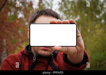 Nahaufnahme, junger Mann mit leerer Bildschirm Mobiltelefon über gelb grün Hintergrund. Weiß leerer Bildschirm für Design. mockup. Stockfoto