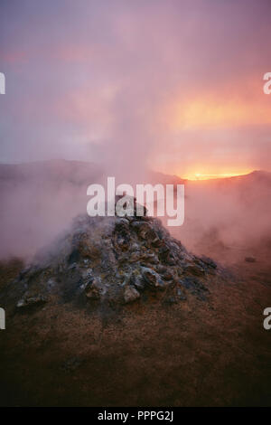 Dampfentlüftung aus einer aktiven Fumarole - das geothermische Gebiet von Namafjall / Hverir in der Nähe des Lake Myvatn bei Dämmerung in Nordisland. Stockfoto