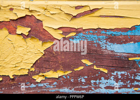 Alte abblätternde Farbe auf dem Brett. Blau und orange Hintergrund. Stockfoto