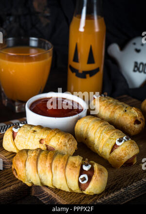 Beängstigend wurst Mumien und Kürbissaft auf dunklem Hintergrund. Stockfoto