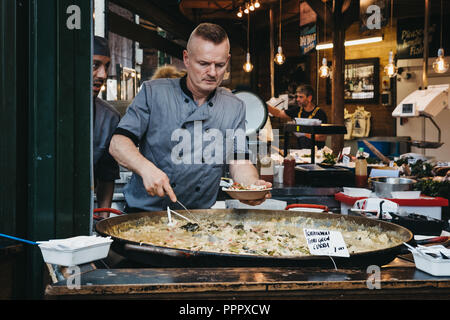 London, UK - 17. September 2018: Verkäufer, einen Teil der Grünen Thai Curry in eine Schüssel zu einem Street Food stand in Borough Market, einem der größten Ein Stockfoto