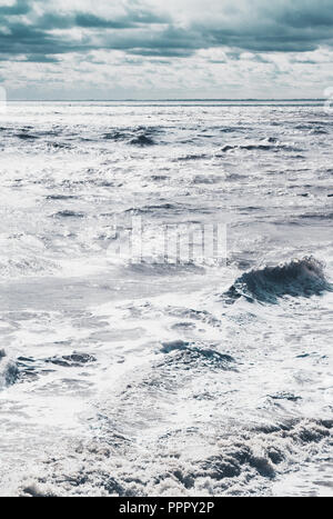 Bewölktem Himmel mit Wellen auf dem Meer in Rollen zu Ufer Stockfoto