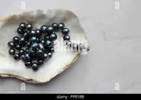 Makro Foto von Black Pearl Beads mit Steinen eine Shell, Marmor Hintergrund Stockfoto