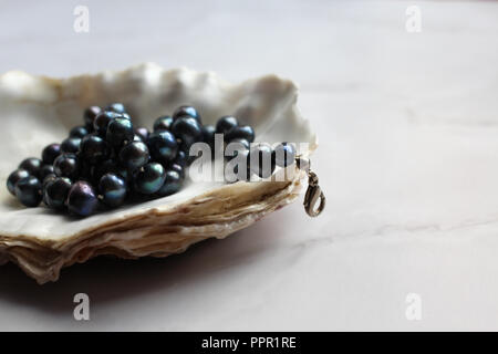 Makro Foto von Black Pearl Beads mit Steinen eine Shell, Marmor Hintergrund Stockfoto