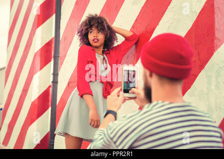 Ruhiger junger Mann, Smartphone und Fotos von seiner Freundin Stockfoto