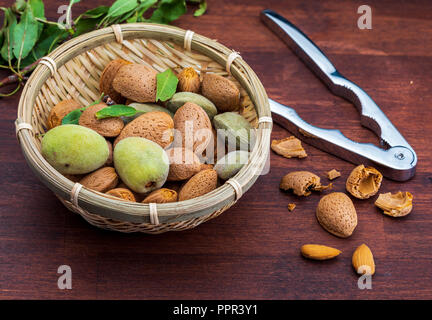 Rohe Mandeln, geschält, mit Schale, Haut (almendrucos) und Mandel Blätter. Auf dunklen Hintergrund. Stockfoto
