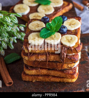 Fried Chocolate French Toast mit Stücken von Bananen auf braunem Holz- Board Stockfoto