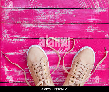 Frau Rosa Turnschuhe mit ungebundenen Schnürsenkel auf einem rosa Holz- Hintergrund des Boards, leeren Raum, Ansicht von oben Stockfoto