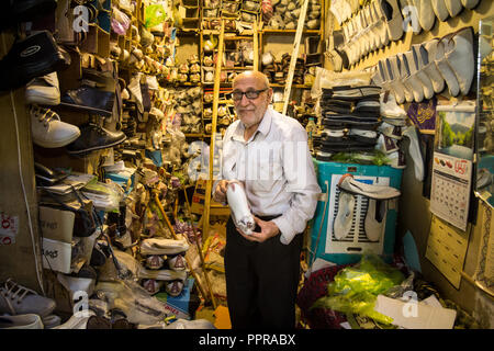 ISFAHAN, IRAN - August 8, 2015: Alte iranische Schuster einen seiner Schuhe zu verkaufen in seinem Geschäft in der Isfahan überdachten Bazar Markt, der eine zeigt Stockfoto