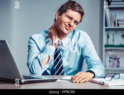 Mitarbeiter leidet unter starken Schmerzen im Hals. Foto der Mann bei der Arbeit im Büro. Medizinisches Konzept. Stockfoto