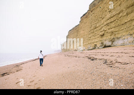 Man Walking am Strand - Burton Bradstock Stockfoto