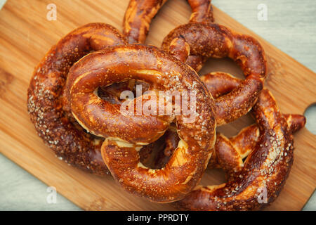 Frisch gebackene Hausgemachte weiche Brezel mit Salz auf hölzernen Schneidebrett Stockfoto