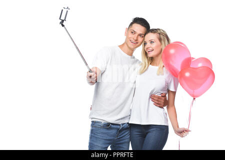 Paar mit Ballons, Foto mit Smartphone und selfie Stick isoliert auf weißem Stockfoto