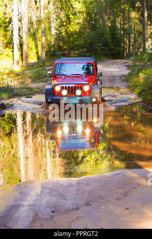 St. Petersburg, Russland - 2013 Juli 30 - Jeep Wrangler Rubicon Überqueren einer großen und tiefen Pfütze im Wald Stockfoto