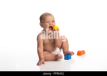 Eine lachende sieben Monate alten Baby Junge spielt mit Holzblöcken. Im Studio auf einem weißen, nahtlose Kulisse erschossen. Stockfoto