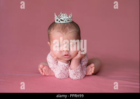 Eine schöne, Schlafen, neugeborene Mädchen mit einem Strass Tiara. Im Studio mit einem rosa Hintergrund. Stockfoto