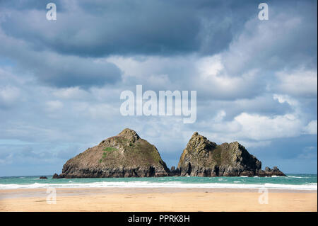 Möwe oder Carters von Felsen, Holywell Bay in der Nähe von Newquay, Cornwall. Iconic twin Inselchen mit Moody Himmel Hintergrund. Stockfoto