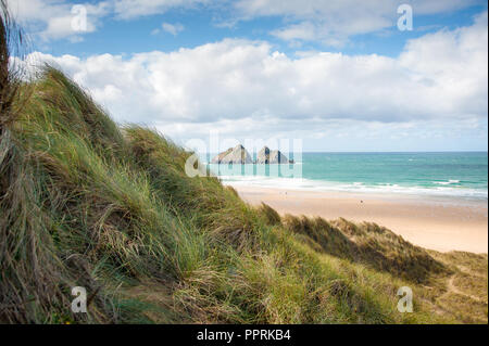 Möwe oder Carters von Felsen, Holywell Bay in der Nähe von Newquay, Cornwall. Küstenlandschaft mit Gras bedeckte Dünen, felsigen kleinen Inseln und blauen bewölkten Himmel Hintergrund. Stockfoto