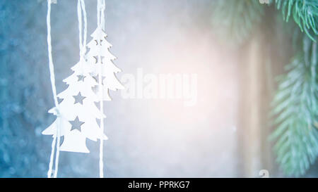 Zwei kleine weiße Weihnachten Bäume hängen auf dem Hintergrund einer grauen Wand mit grünen Weihnachtsbaum Filialen schliessen. Weihnachten Hintergrund Winter neues Jahr Landschaft Hintergrund. Stockfoto