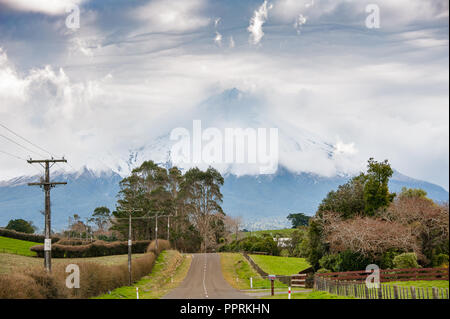 Mount Taranaki (Mount Egmont), Egmont National Park, Neuseeland. Ländliche Landschaft, Straße führt zu Mountain semi-in Cloud mit grünen Vordergrund verdeckt. Stockfoto