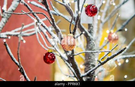Winter Baum ohne Blätter mit Schnee bedeckt mit kleinen dekorativen roten Kugeln close-up. Weihnachten Winter neues Jahr Landschaft Hintergrund. Konzept Stockfoto