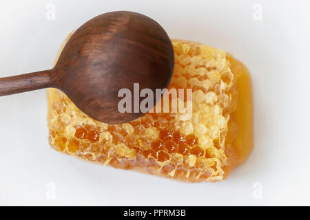 Organische Honigwaben, Löffel aus Holz auf weißem Hintergrund. Natürliche Inhaltsstoffe, Bienenprodukte für Lebensmittel Konzept Stockfoto