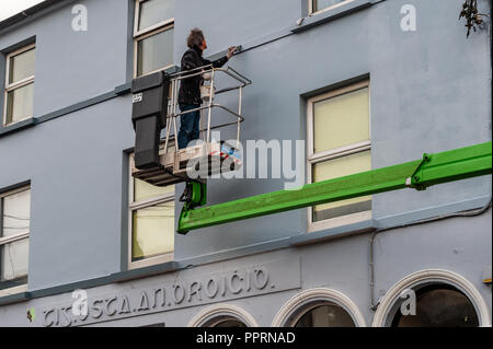 Maler und Dekorateur auf einer erhöhten Plattform Malerei ein Gebäude in Bantry, West Cork, Irland. Stockfoto