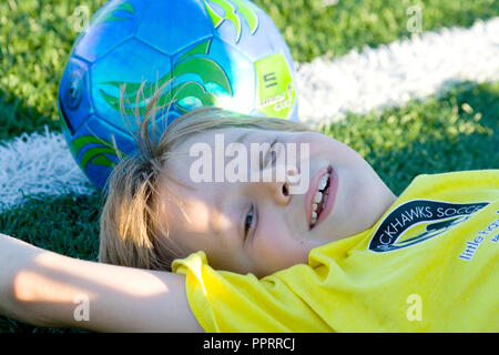 Junge Alter neun Verlegung auf Masse glücklich erschöpft nach Fußball spielen. St. Paul Minnesota MN USA Stockfoto