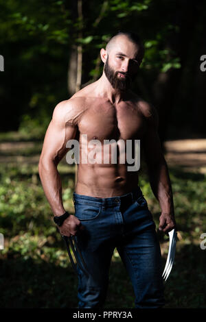 Porträt eines körperlich Fit Wolverine mit Krallen zeigt Seine gut trainierten Körper - Muskulös athletisch Bodybuilder Fitness Superhelden posiert im Freien Stockfoto