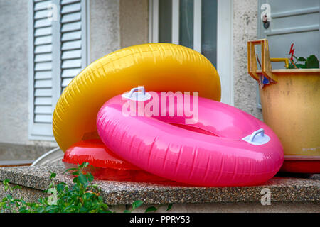 Aufblasbare Strand schwimmt in Form donut Ringe auf der Veranda bereit für Spaß am Strand Rest außerhalb eines Hauses in Vrbnik in Kroatien an der Adria Stockfoto