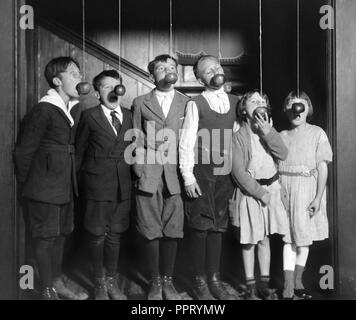 Eine Gruppe von Jungen und Mädchen spielen eine Halloween Spiel der beißenden Äpfel auf Strings, Ca. 1922. Stockfoto