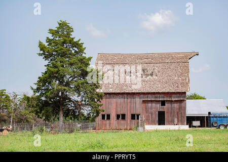 Alte verblasste rote hölzerne Scheune auf dem Land außerhalb von Wichita, Kansas, USA. Stockfoto
