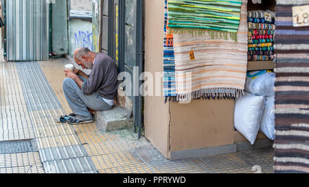 Athen Griechenland/August 17, 2018: Frau walking Down Down Flohmarkt mit Graffiti auf den geschlossenen Türen geschlossen Stockfoto