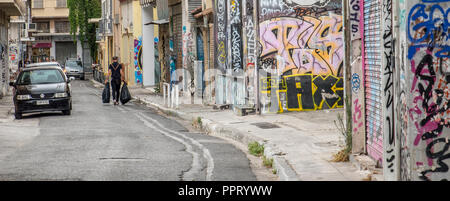 Athen Griechenland/August 17, 2018: Mann in Schwarz Fuß mit zwei schwarzen Müllsäcke auf der Straße Stockfoto