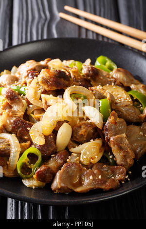 Dak-ttongjip ist eine koreanische Gericht durch Rühren, Braten Huhn gizzard mit Gewürzen close-up auf einem Teller auf dem Tisch. Vertikale Stockfoto